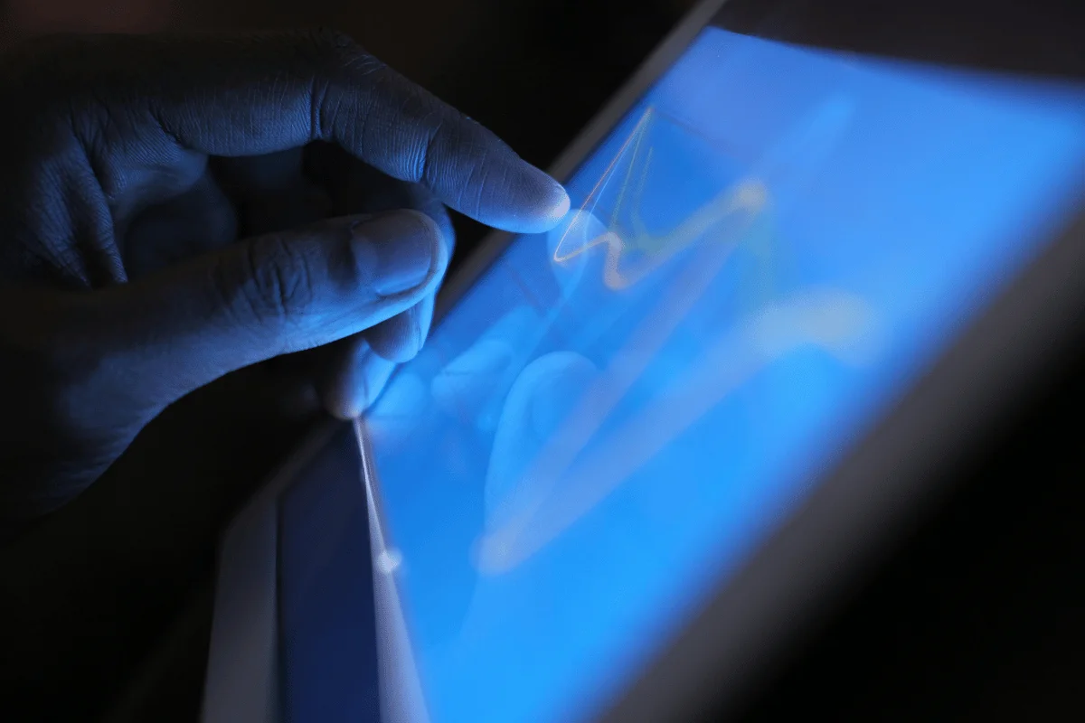 A hand gently touches a glowing blue tablet screen showing a line graph, creating a sense of focus and digital interaction.