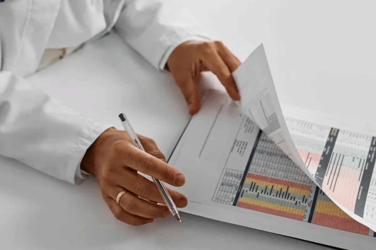 Person organizing medical coding documents and files on desk for revenue cycle management workflow optimization.