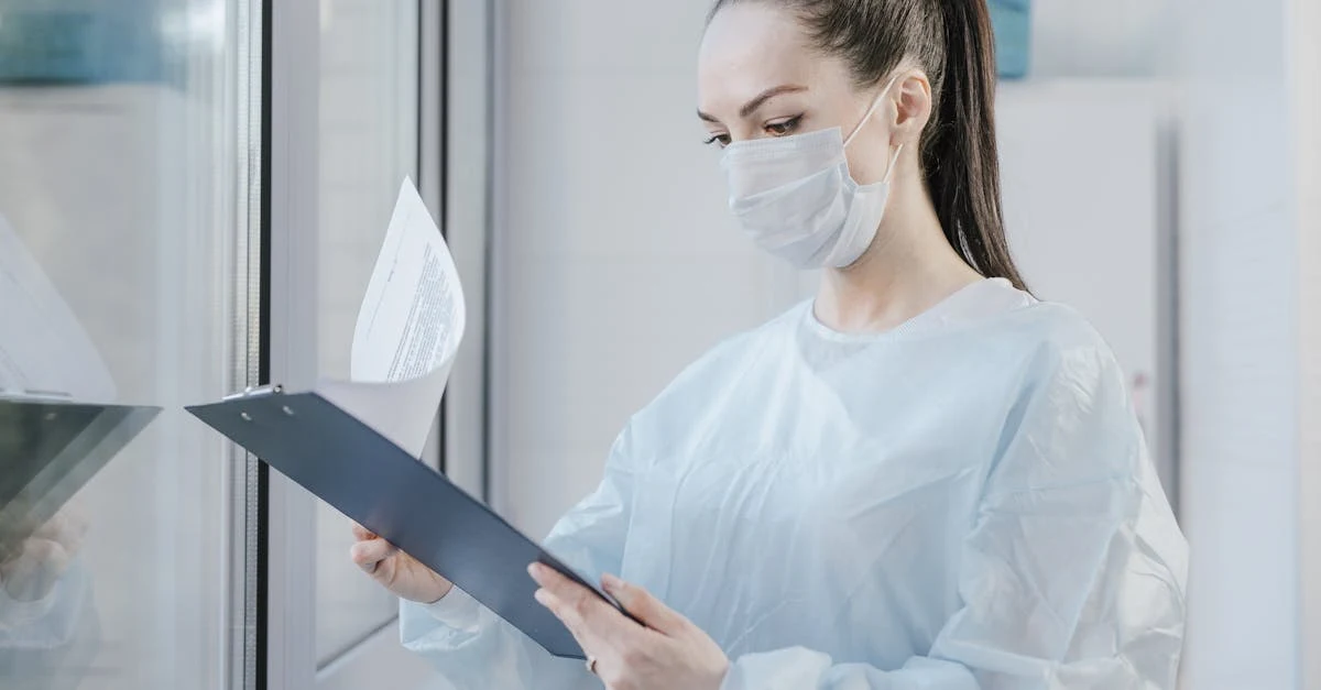 Healthcare professional in mask reviewing clipboard with medical coding accuracy documentation in clinical office setting.