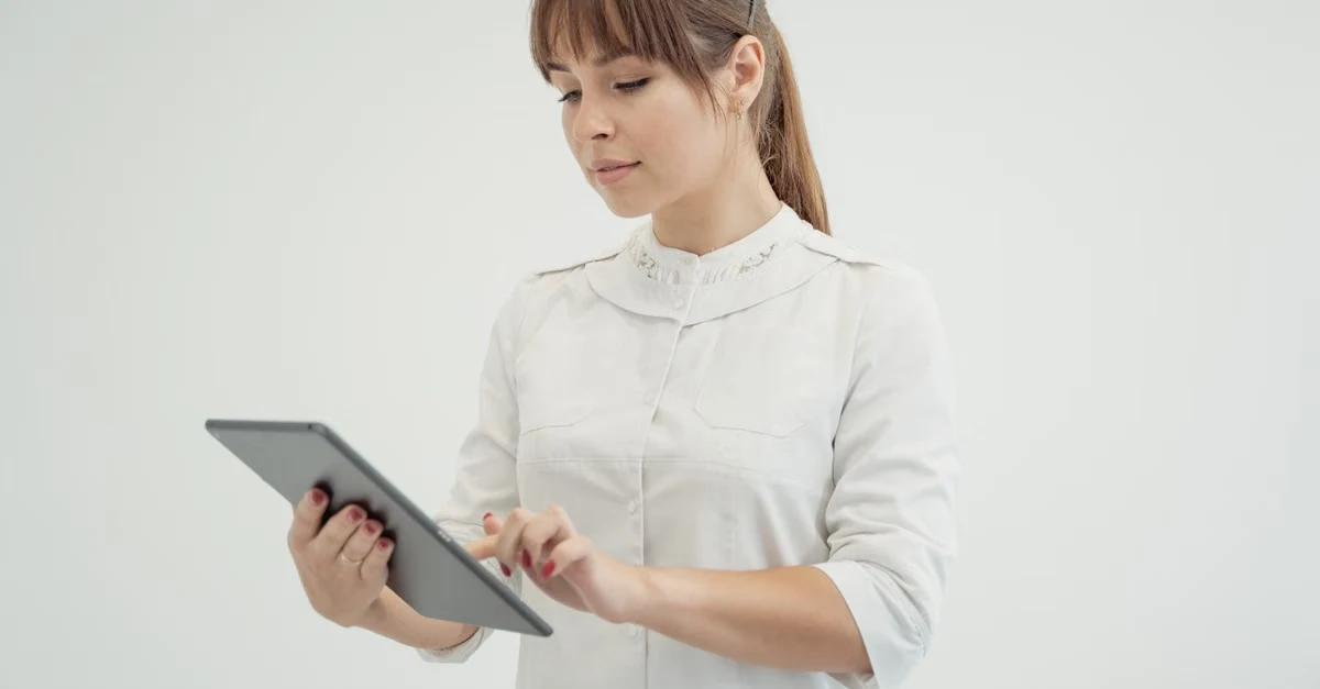 Healthcare professional reviewing medical coding compliance data on digital tablet against white background.