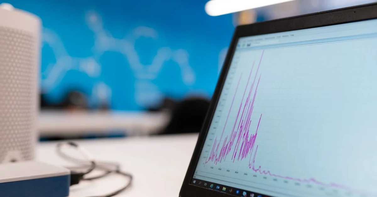 Laptop displaying medical billing calculator analytics graph with purple data visualization in modern office workspace.
