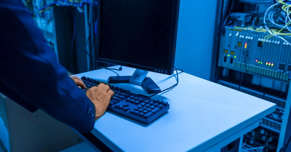 IT administrator managing revenue cycle management automation systems in server room with network equipment.