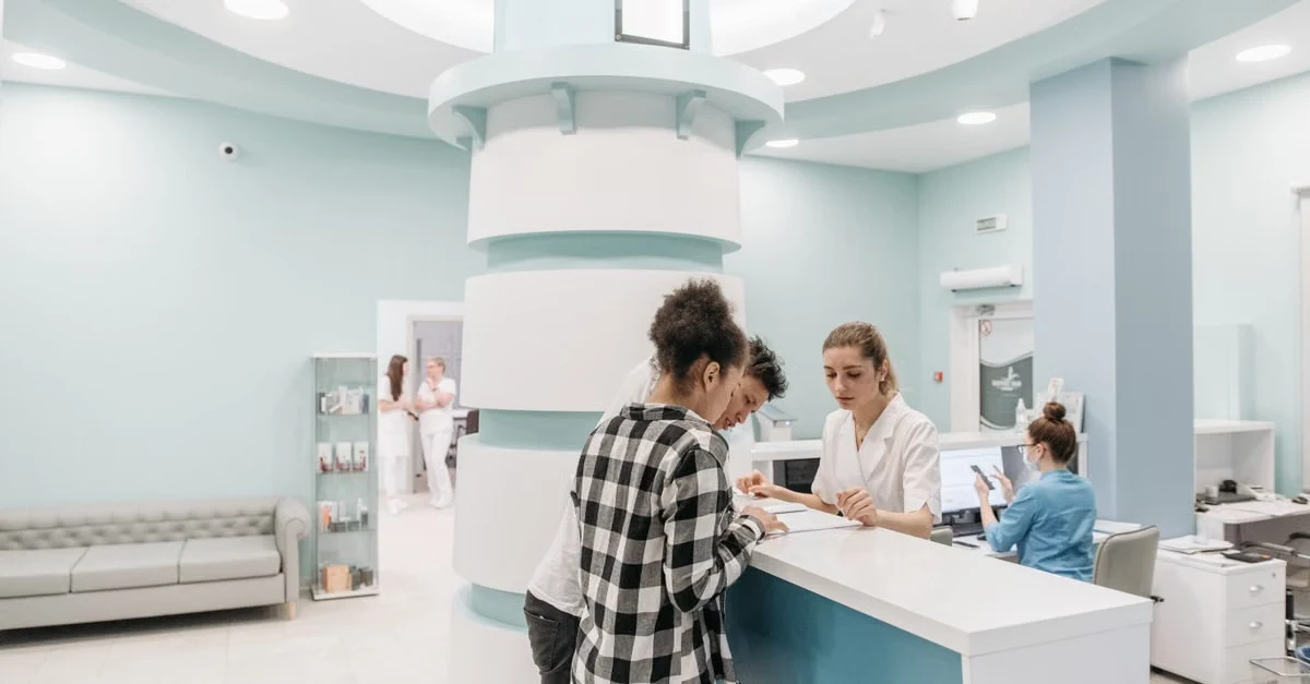 Patient checking in at modern medical reception desk with healthcare workflow automation systems in clinic lobby.