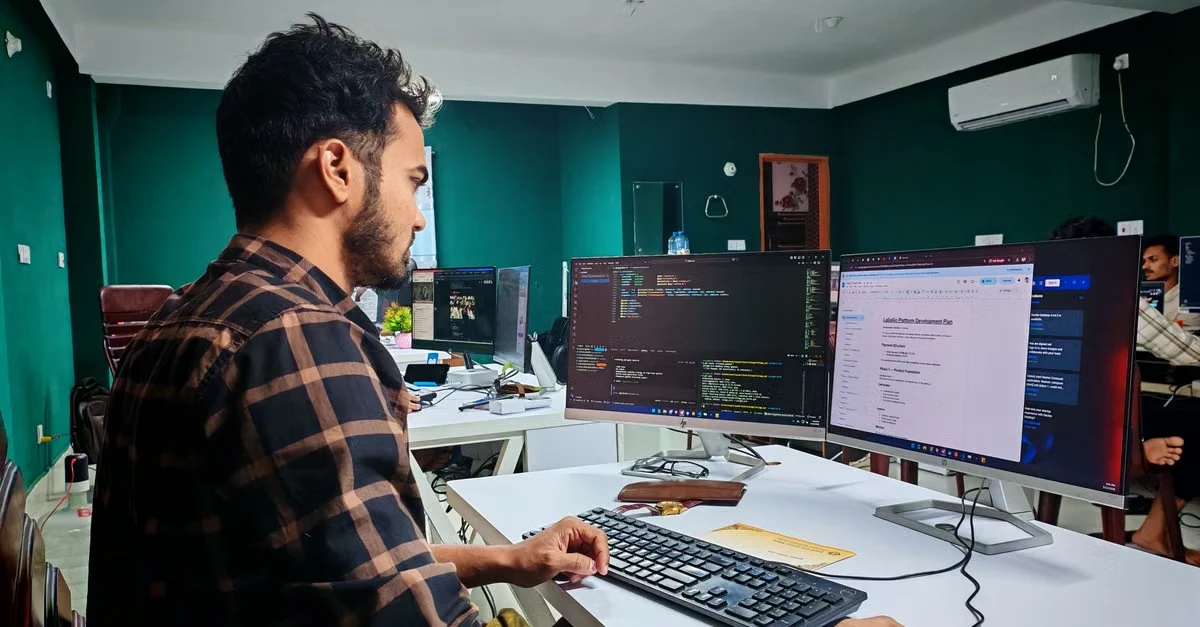 Male coder at desk with dual monitors reviewing medical coding risk adjustment documentation and healthcare data.