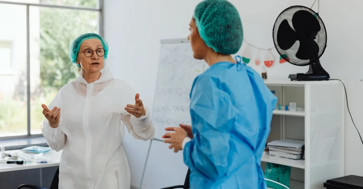 Two healthcare professionals discussing AI scribe pediatrics implementation in clinic office with whiteboard notes.