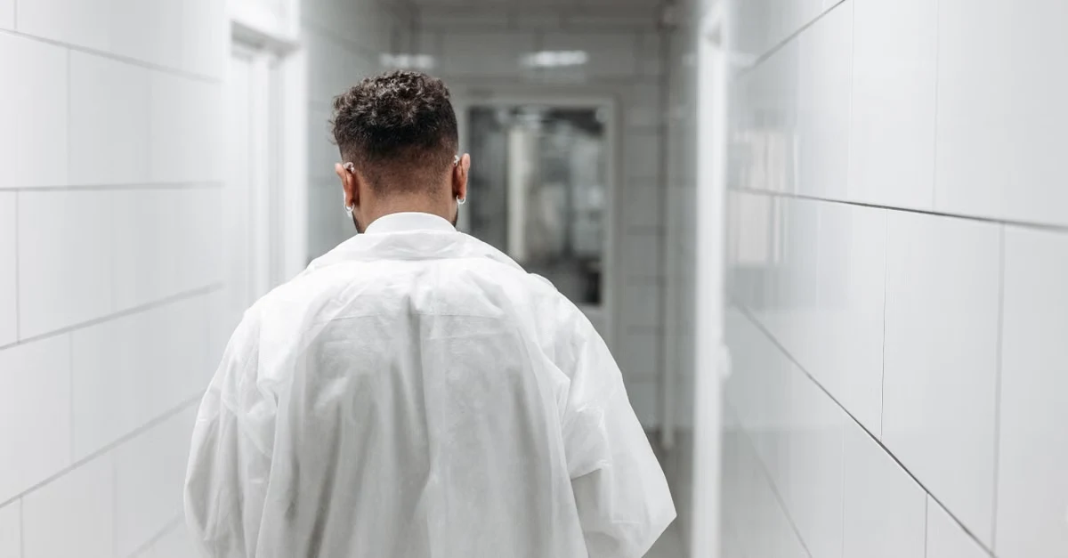 Doctor in white coat walking down clinical hallway, representing AI scribe cardiology documentation workflow beyond exam.