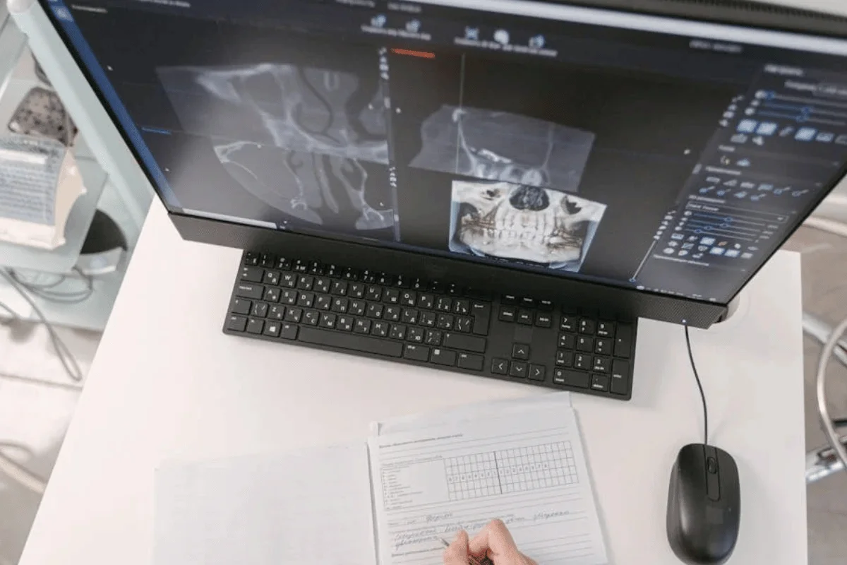 Medical professional reviewing patient charts and computer screen displaying medical coding productivity standards data.