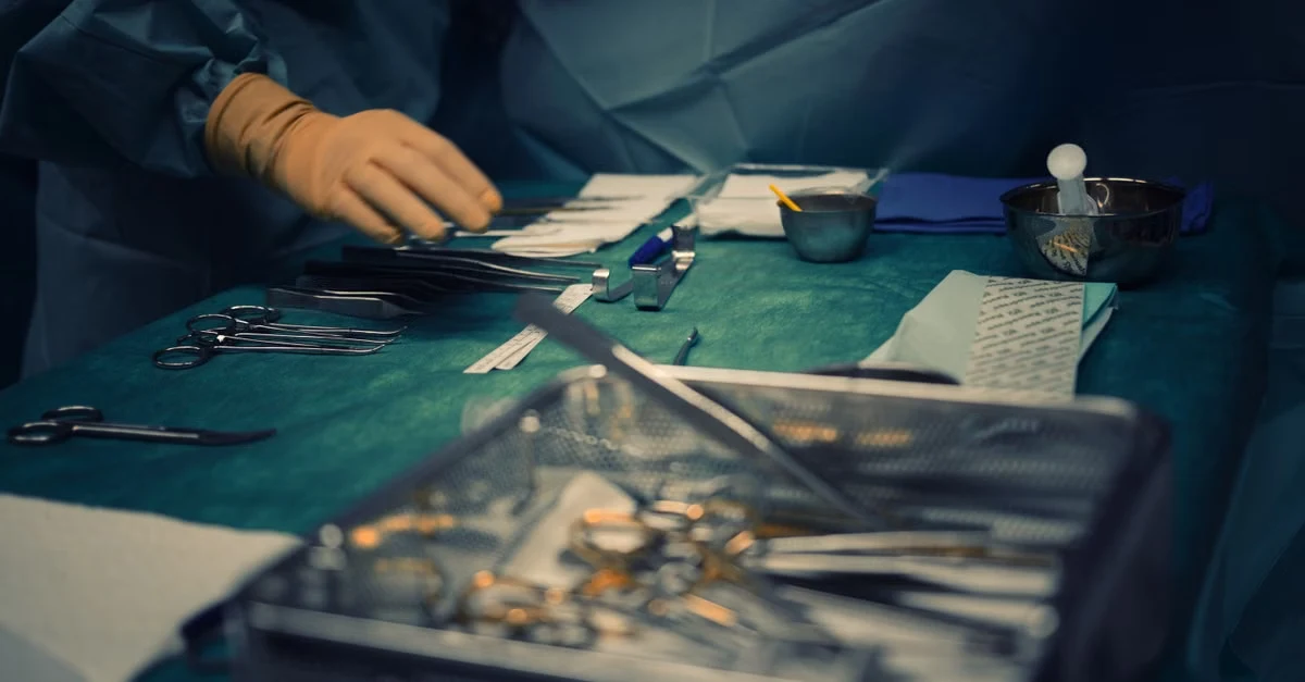 Surgeon organizing surgical instruments on sterile table during hand surgery coding procedure.