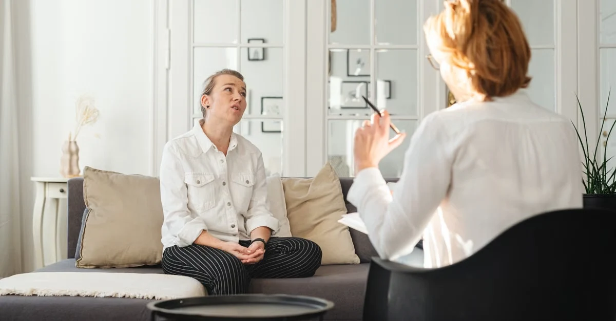 Psychiatrist taking notes during patient consultation session in modern therapy office.